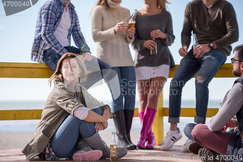 Image of Group of friends having fun on autumn day at beach