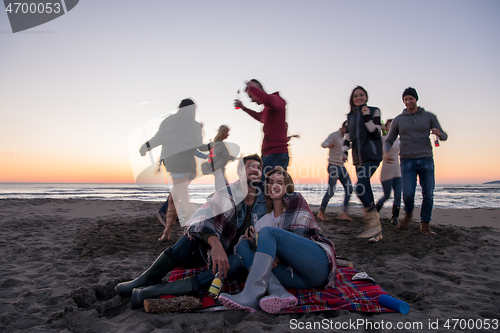 Image of Couple enjoying with friends at sunset on the beach