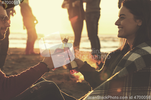 Image of Couple enjoying with friends at sunset on the beach