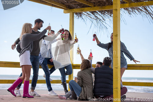 Image of Group of friends having fun on autumn day at beach