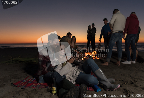 Image of Couple enjoying bonfire with friends on beach