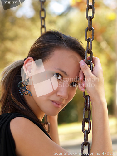 Image of Young asian american woman on swing chains