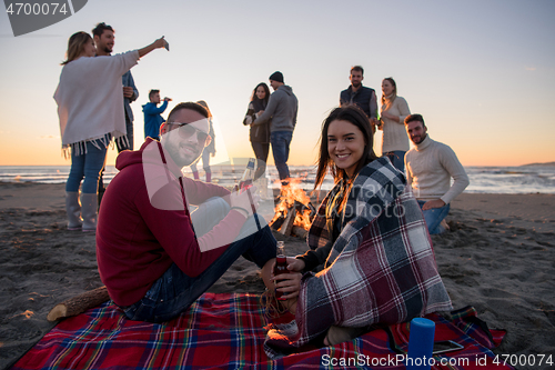 Image of Couple enjoying with friends at sunset on the beach