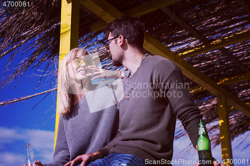 Image of young couple drinking beer together at the beach