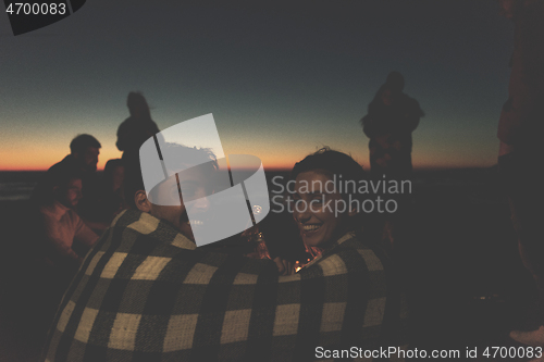 Image of Couple enjoying with friends at sunset on the beach