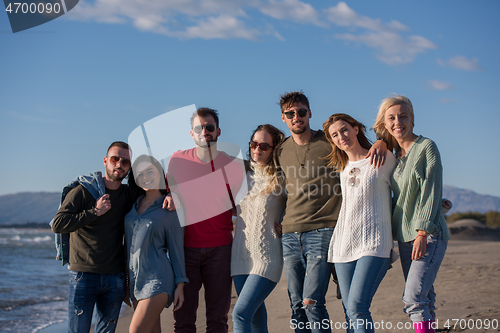 Image of portrait of friends having fun on beach during autumn day