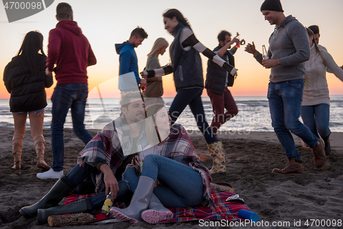 Image of Couple enjoying with friends at sunset on the beach