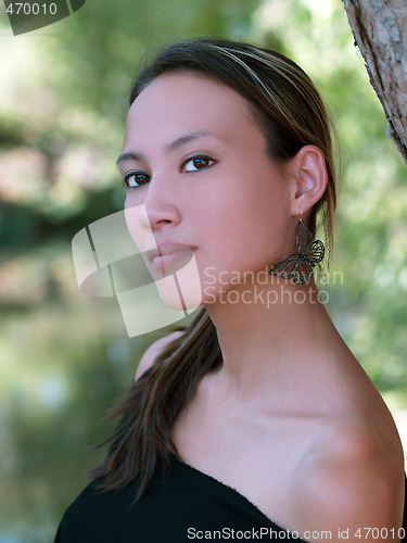 Image of Portrait of young woman outdoors with green leaves