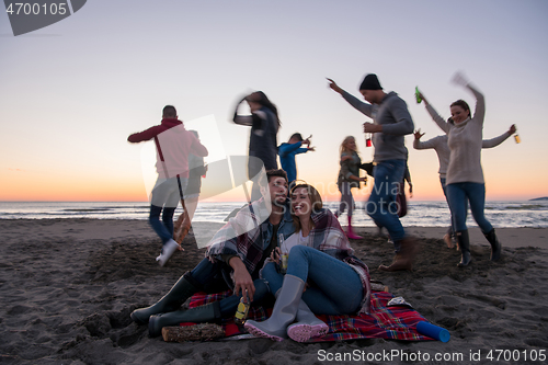 Image of Couple enjoying with friends at sunset on the beach