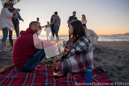 Image of Couple enjoying with friends at sunset on the beach