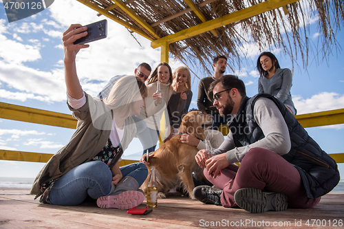 Image of Group of friends having fun on autumn day at beach