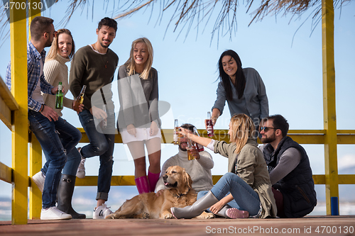 Image of Group of friends having fun on autumn day at beach