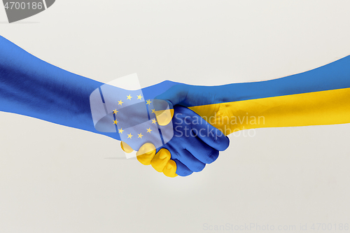 Image of Two hands. Flag of the European Union. Flag of Ukraine.