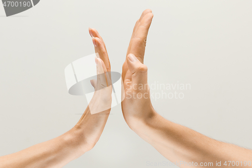 Image of Male and female hands demonstrating a gesture of getting touch isolated on gray background