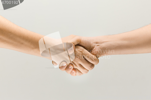 Image of Two male hands shaking isolated on grey studio background