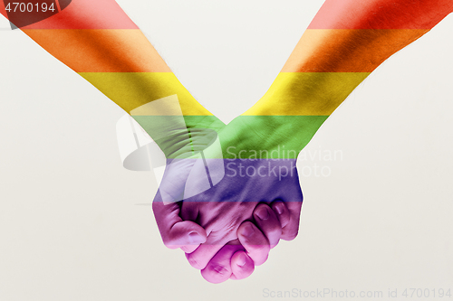 Image of  loseup of a gay couple holding hands, patterned as the rainbow flag