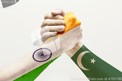 Image of Two male hands competing in arm wrestling colored in Pakistan and India flags