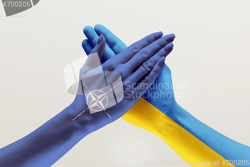 Image of Male and female hands colored in flags of Ukraine and NATO