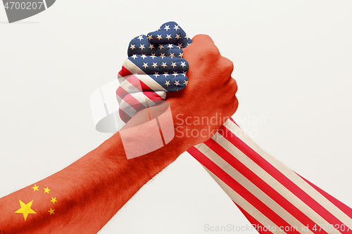 Image of Two male hands competing in arm wrestling colored in China and America flags