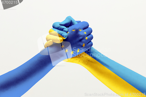 Image of Two hands. Flag of the European Union. Flag of Ukraine.