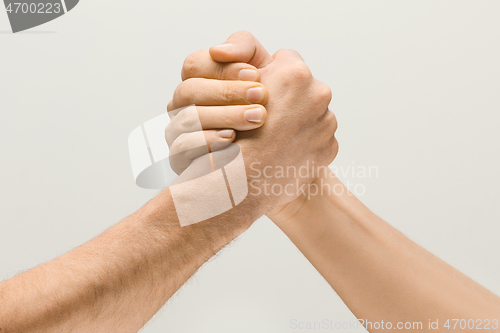 Image of Two male hands competion in arm wrestling isolated on grey studio background