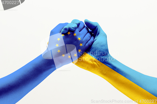 Image of Two hands. Flag of the European Union. Flag of Ukraine.