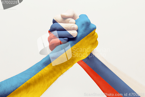 Image of Two hands. Flag of Russian Federation. Flag of Ukraine.