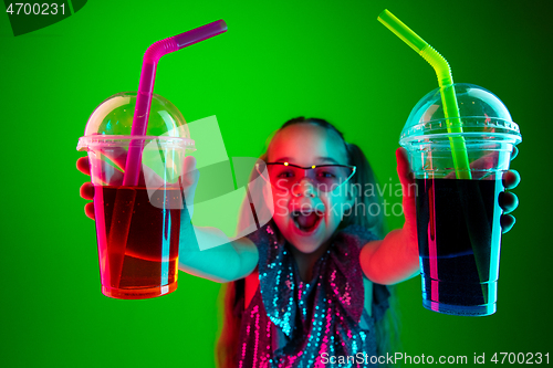 Image of The happy teen girl standing and smiling against green lights background.