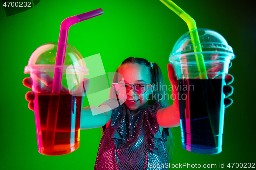 Image of The happy teen girl standing and smiling against green lights background.