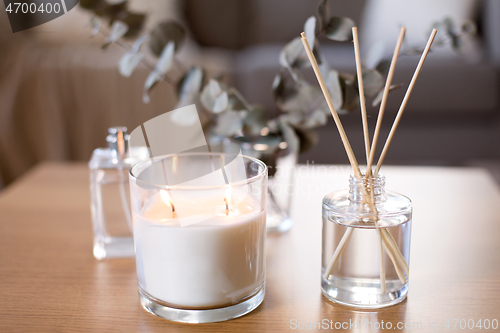 Image of aroma reed diffuser, burning candle and perfume