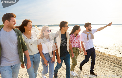 Image of happy friends walking along summer beach