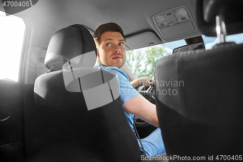 Image of man or driver driving car and looking back