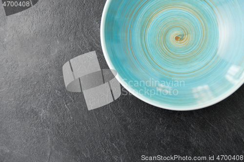 Image of close up of blue ceramic plate on slate background