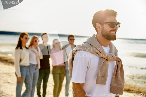 Image of happy man with friends on beach in summer