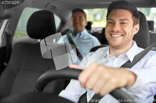 Image of male taxi driver driving car with passenger