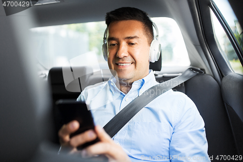 Image of passenger with headphones using smartphone in car