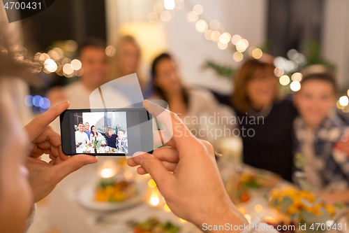 Image of man taking picture of family at dinner party