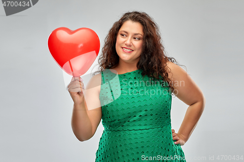 Image of happy woman holding red heart shaped balloon