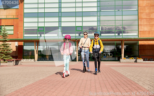 Image of happy school children with mother riding scooters