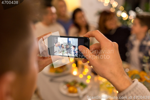 Image of man taking picture of family at dinner party