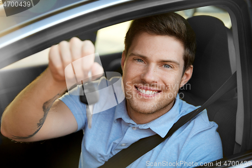 Image of smiling man or driver with key sitting in car