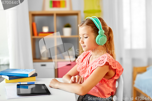 Image of girl in headphones with tablet computer at home