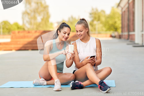 Image of sporty women or friends with smartphone on rooftop