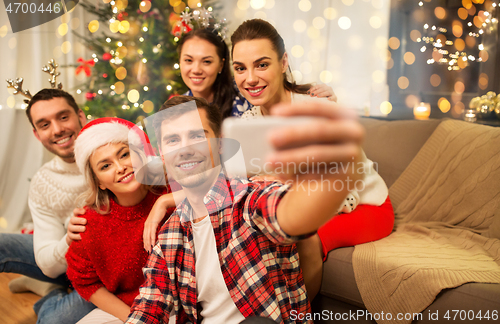 Image of friends celebrating christmas and taking selfie