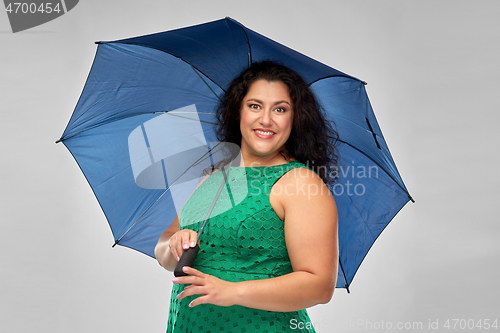 Image of happy woman in green dress with blue umbrella