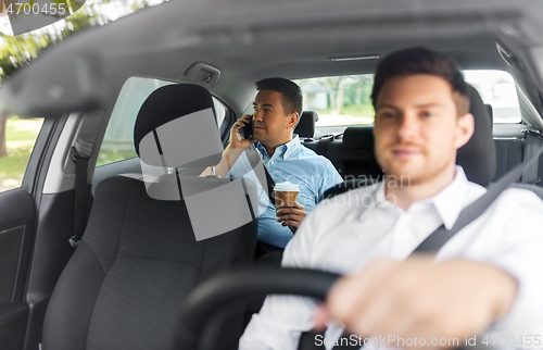 Image of male passenger with coffee calling on phone in car