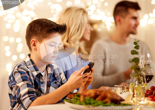 Image of boy with smartphone at family dinner party