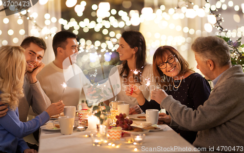 Image of family with sparklers having dinner party at home