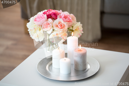 Image of candles burning on table and flowers at cozy home