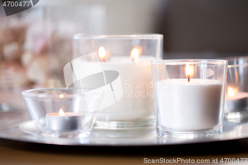 Image of burning white fragrance candles on tray on table